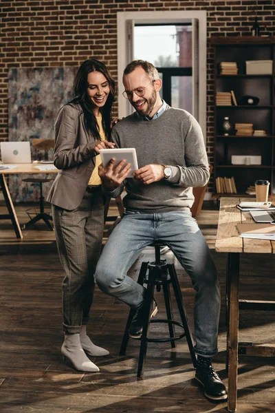 Пара улыбающихся коллег обсуждают работу в современном лофт-офисе — стоковое фото