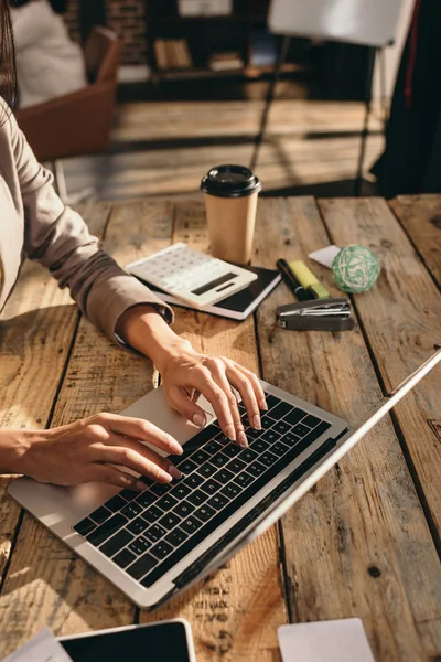 Vue recadrée des mains féminines tapant sur ordinateur portable au bureau avec fournitures de bureau — Photo de stock