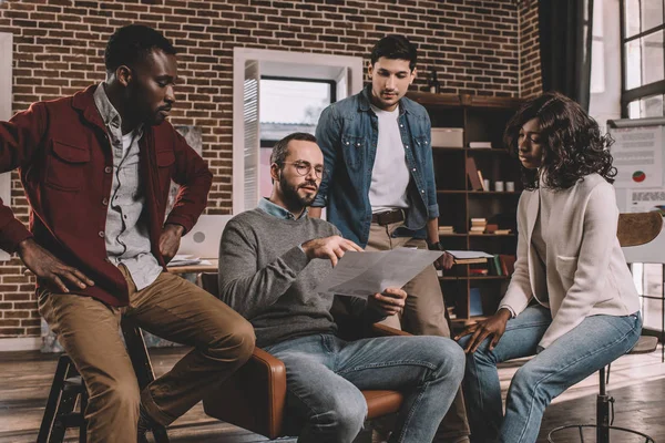 Grupo multiétnico centrado de compañeros de trabajo discutiendo juntos nuevo proyecto en la oficina loft moderno - foto de stock