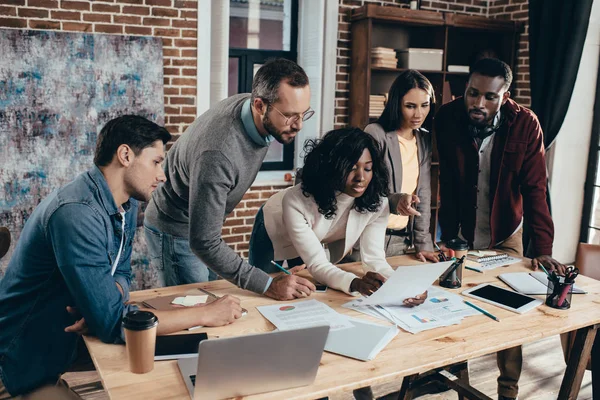 Konzentrierte multiethnische Gruppe von Mitarbeitern, die sich treffen und gemeinsam ein neues Projekt im modernen Loft-Büro diskutieren — Stockfoto