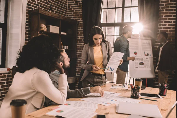 Focused multiethnic group of colleagues working together on new project in modern loft office with backlit — Stock Photo