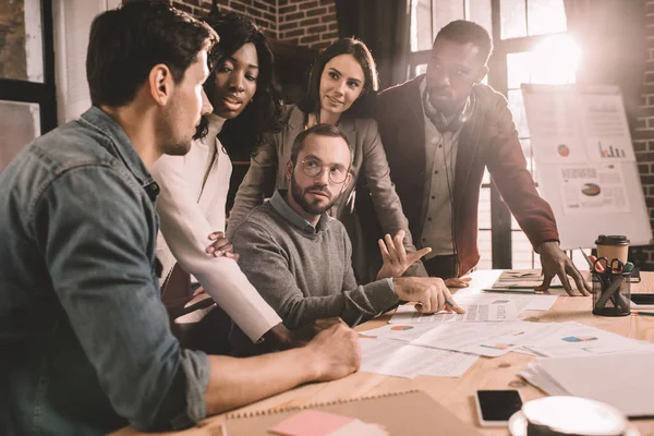 Concentrated multiethnic group of colleagues working together on new project in modern loft office with backlit — Stock Photo