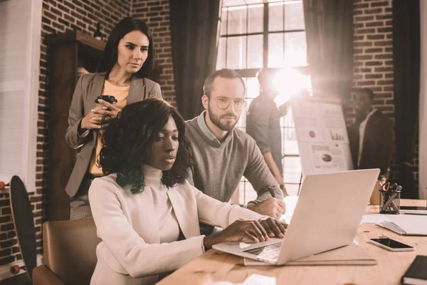 Konzentrierte multiethnische Gruppe von Kollegen, die gemeinsam an einem neuen Projekt in einem modernen Loft-Büro mit Hintergrundbeleuchtung arbeiten — Stockfoto