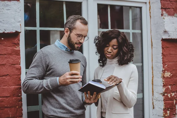 Focused multiethnic colleagues talking about new project while having coffee — Stock Photo