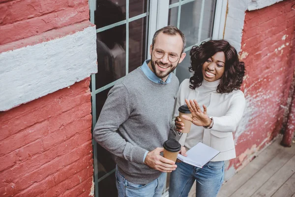 Lächelnde multiethnische Kollegen, die über Arbeit und Kaffee reden — Stockfoto