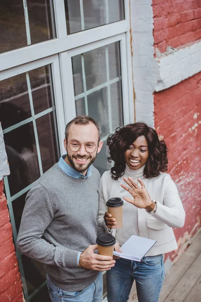 Happy multiethnic colleagues talking about work and having coffee — Stock Photo