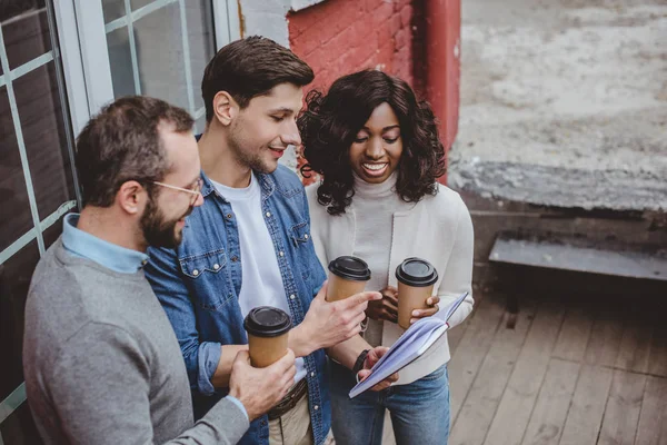 Colegas multiétnicos hablando de trabajo y tomando café - foto de stock