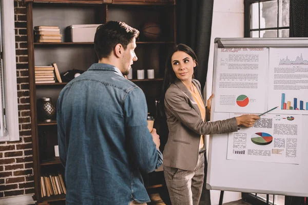 Exitoso par de colegas discutiendo el proyecto utilizando gráfico en la oficina loft - foto de stock