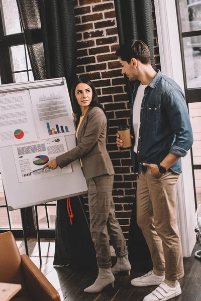 Concentrated couple of colleagues discussing project using marketing graph in loft office — Stock Photo