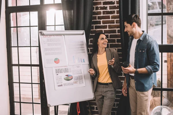 Enthousiaste couple de collègues souriant et désagréable projet en utilisant le graphique dans le bureau loft — Photo de stock