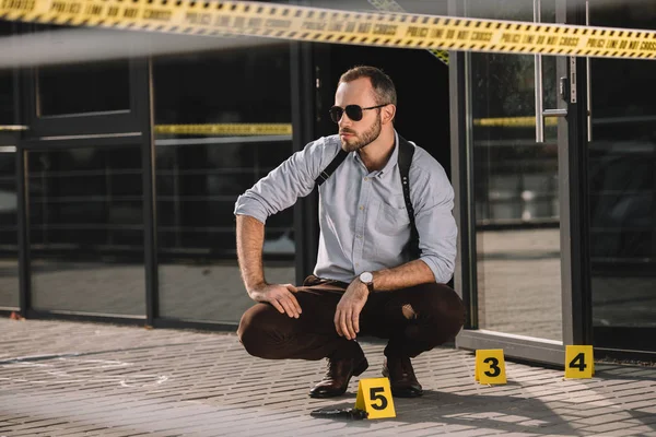 Pensativo detetive masculino sentado na cena do crime — Fotografia de Stock