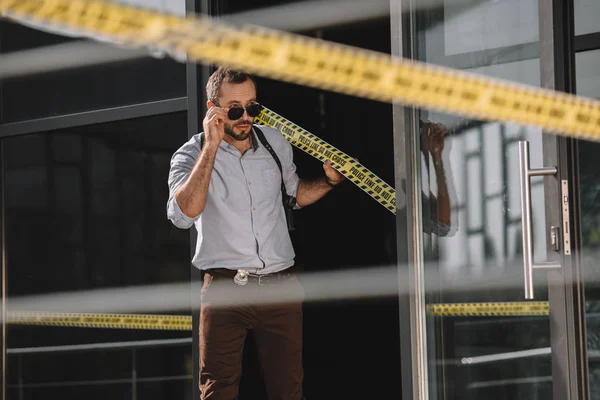 Male detective straightening sunglasses holding on the cross line — Stock Photo