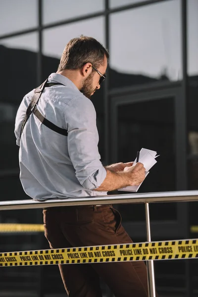 Back view of male detective in sunglasses making notes — Stock Photo