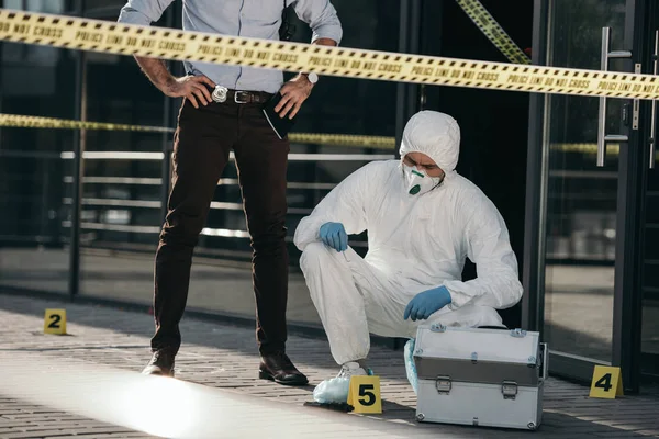 Cropped view of male detective looking at work of criminilogist — Stock Photo