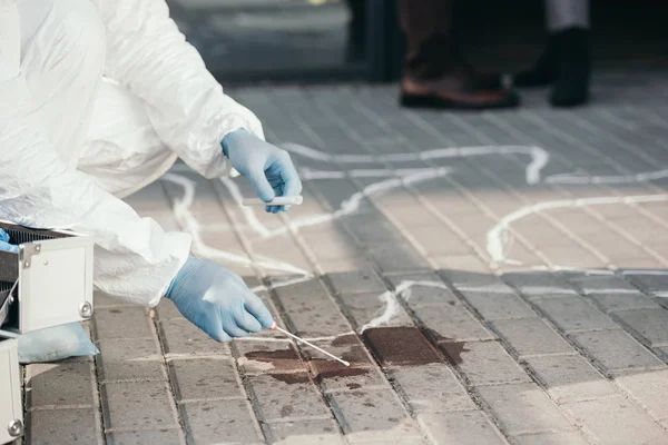 Criminologue masculin en combinaison de protection et gants en latex prélevant des échantillons de sang sur les lieux du crime — Photo de stock