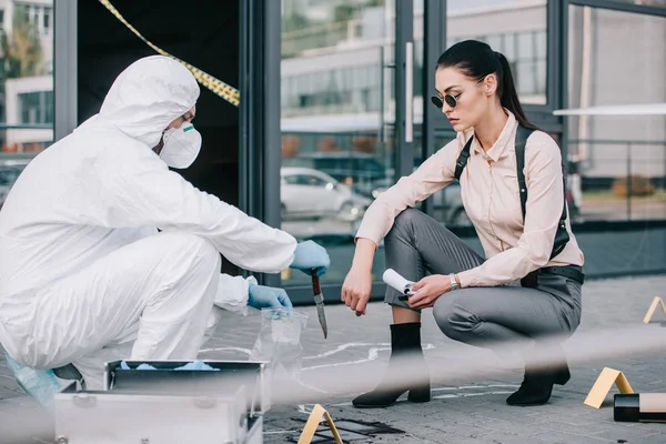 Criminologist shows knife as a murder weapon to female detective — Stock Photo