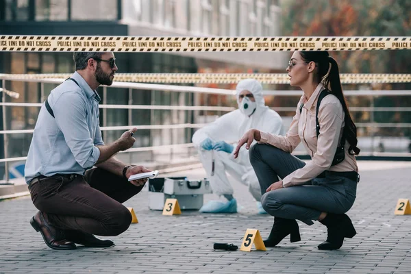 Female and male detectives in sunglasses share their opinions at crime scene — Stock Photo