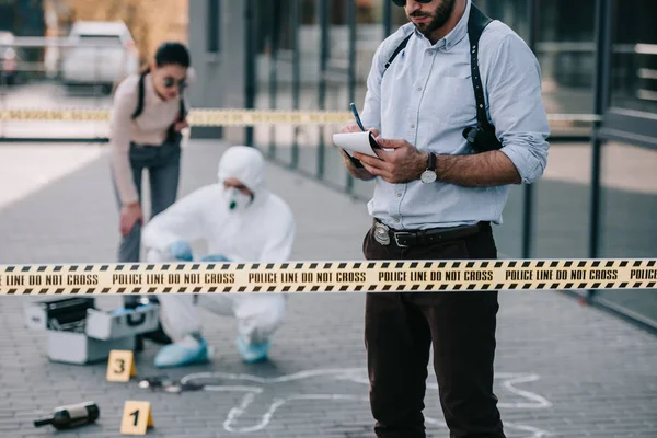 Female and male detectives with criminologist at crime scene — Stock Photo