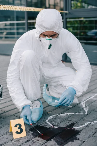 Criminólogo masculino en traje de protección que toma una muestra de sangre - foto de stock