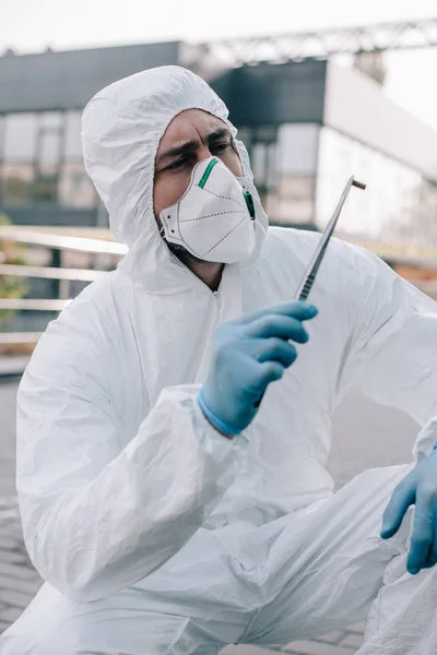 Male criminologist in protective suit and latex gloves looking at evidence at crime scene — Stock Photo