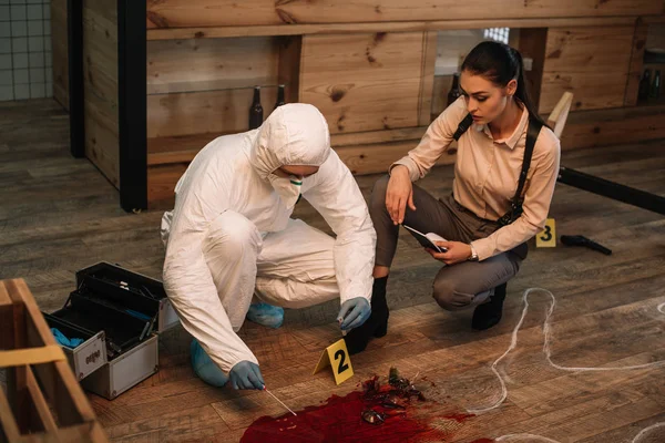 Investigadora forense e detetive feminina tomando notas e examinando a cena do crime juntas — Fotografia de Stock
