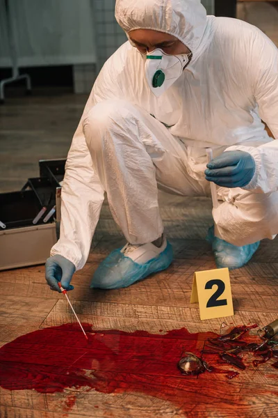 Vista recortada del investigador forense en guantes de látex tomando muestras de sangre en la escena del crimen - foto de stock