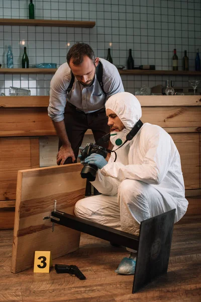 Investigador forense mostrando fotos en cámara a detective masculino en la escena del crimen - foto de stock