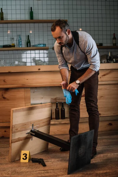 Detective masculino recogiendo evidencia arma en la escena del crimen - foto de stock