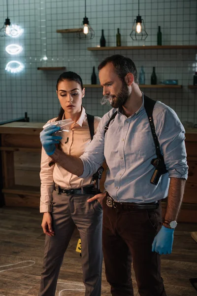 Concentated female and male detectives discussing evidents and investigating crime scene together — Stock Photo
