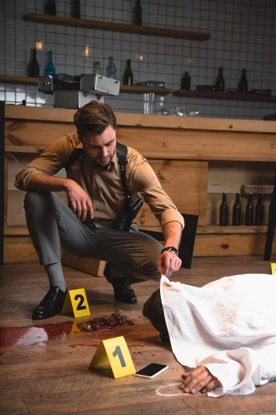 Detective masculino examinando cadáver en la escena del crimen - foto de stock