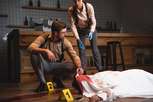 Female and male detectives investigating dead body at crime scene — Stock Photo