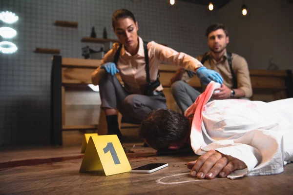 Serious female and male detectives investigating dead body at crime scene — Stock Photo