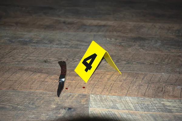 Knife at fresh crime scene with evidence marker on wooden floor — Stock Photo