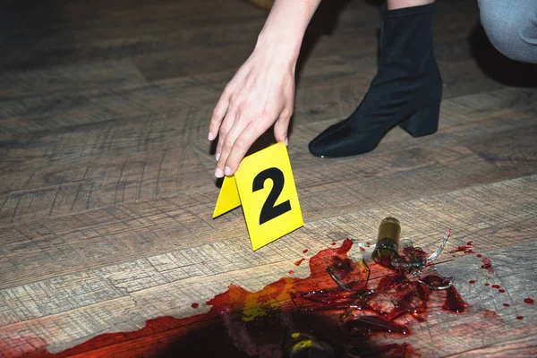 Vue recadrée de la main touchant la marque des preuves sur la scène de crime sanglante — Photo de stock