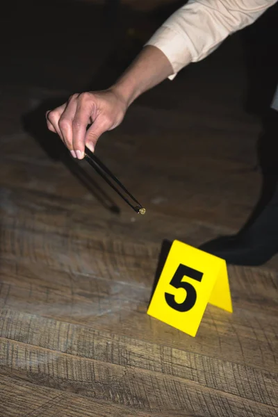 Vista recortada de la mano examinando pruebas en la escena del crimen - foto de stock