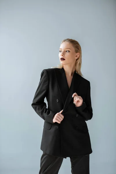 Bella ragazza elegante in posa in abito nero isolato su grigio — Foto stock