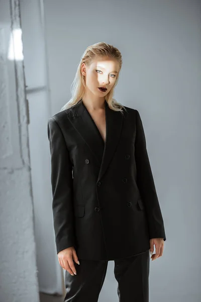 Modello elegante in posa in abbigliamento formale con fascio di luce sul viso su grigio — Foto stock