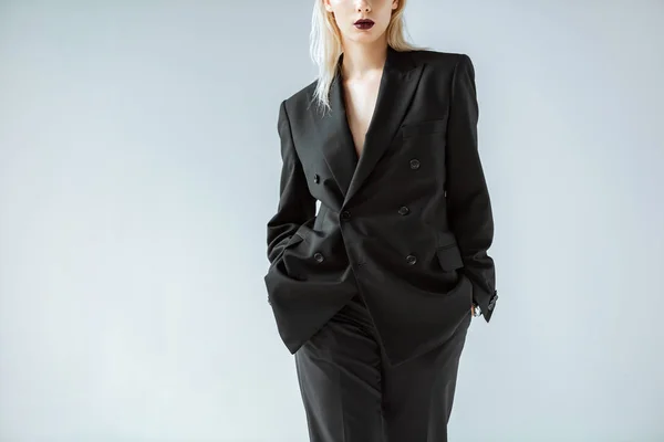 Abgeschnittene Ansicht von modischen Mädchen posiert in schwarzem Anzug isoliert auf grau — Stockfoto