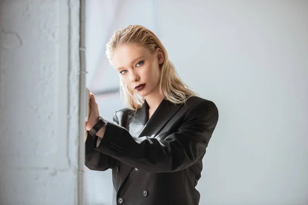 Приваблива блондинка позує в чорному костюмі на сірому — стокове фото