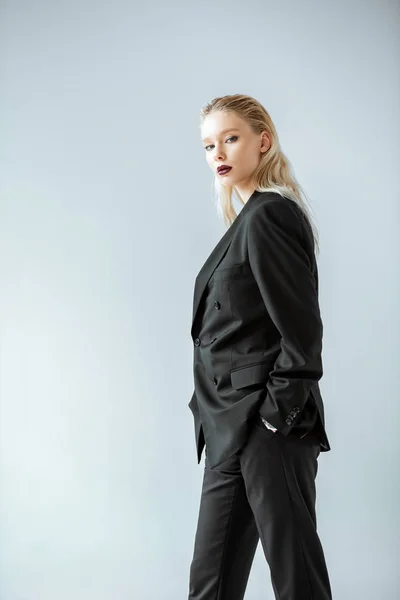 Attraktives stylisches Mädchen posiert in schwarzer formaler Kleidung isoliert auf grau — Stockfoto