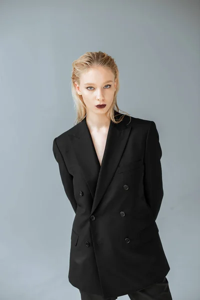 Jovem mulher elegante posando em terno preto isolado no cinza — Stock Photo