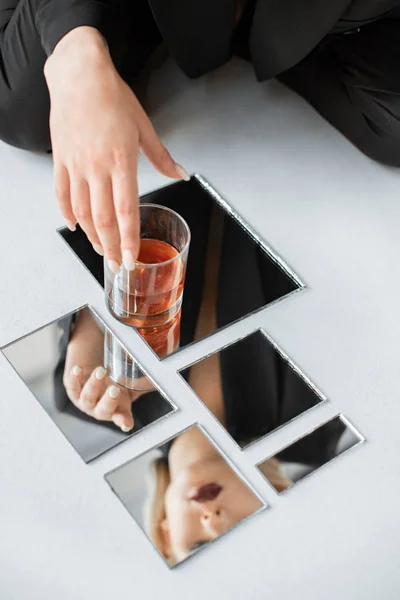 Відображення красивої модної дівчини в дзеркалах зі склянкою віскі — стокове фото