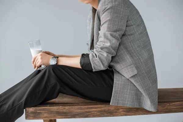 Teilansicht einer modischen Frau in grauer Jacke, die ein Glas Milch isoliert auf grau hält — Stockfoto