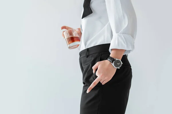 Частичный вид женщины со стаканом виски, показывающий средний палец, изолированный на сером — стоковое фото