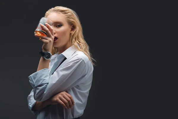 Chica elegante de moda en desgaste formal sosteniendo vaso de whisky, aislado en gris oscuro - foto de stock
