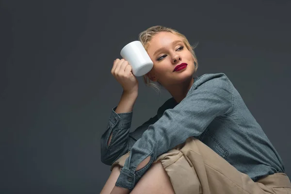 Приваблива елегантна дівчина з чашкою кави ізольована на сірому — стокове фото