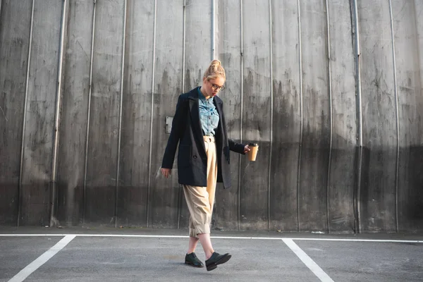 Menina elegante atraente com café para ir andando no estacionamento urbano — Fotografia de Stock