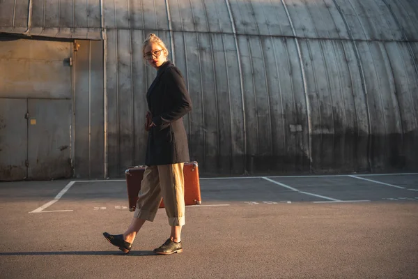 Elegant girl holding retro suitcase on urban parking — Stock Photo
