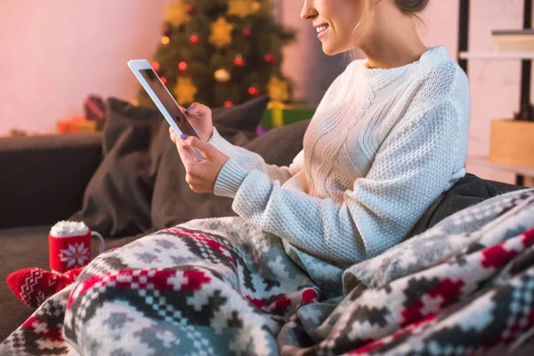 Обрезанный вид женщины, сидящей на диване и с помощью планшета на Рождество время — стоковое фото