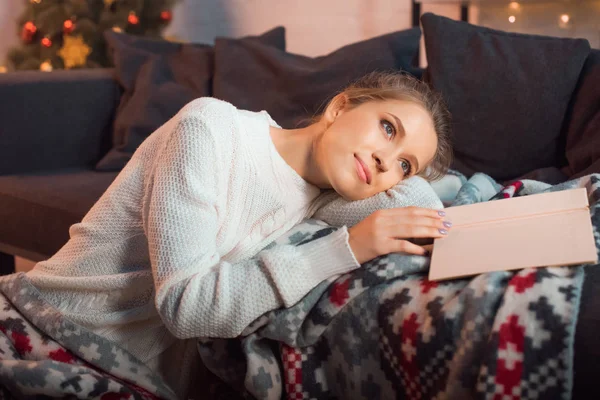 Schöne Frau mit Buch träumt auf dem Sofa — Stockfoto